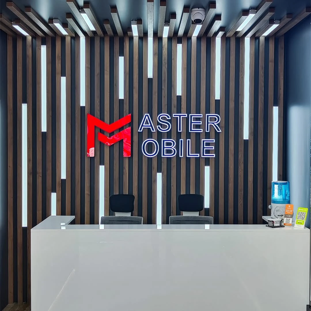 A shop reception area with vertical wooden elements, linear lighting and a dimensional logo. The photos show the overall space and a front view of the branded wall.