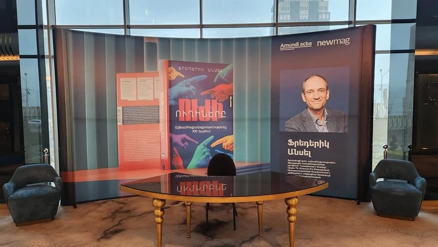 newmag և Amundi–ACBA միջոցառման կոր ֆոնը՝ գրքի պատկերով և հեղինակի դիմանկարով